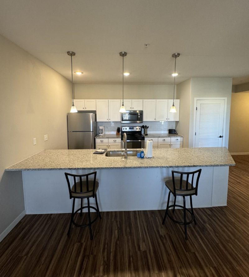 Dining and kitchen area in open-plan apartment with breakfast bar seating.